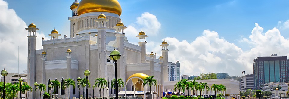Billedet viser en imponerende moské med gyldne kupler mod en blå himmel.