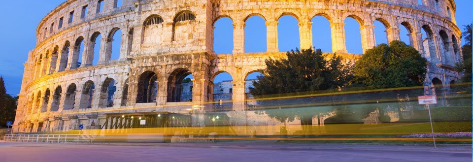 Colosseum i Pula, taget i skumringen med en lang eksponeringstid, der viser lysstrøg fra en bus.